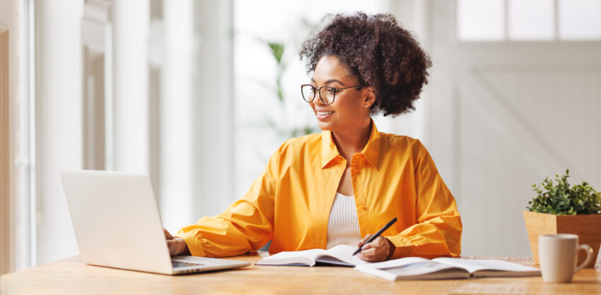 happy woman on computer taking notes