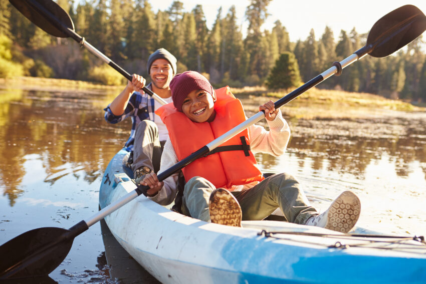 Father And Son Rowing Kayak On Lake